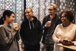 Four people of different races drinking coffee.