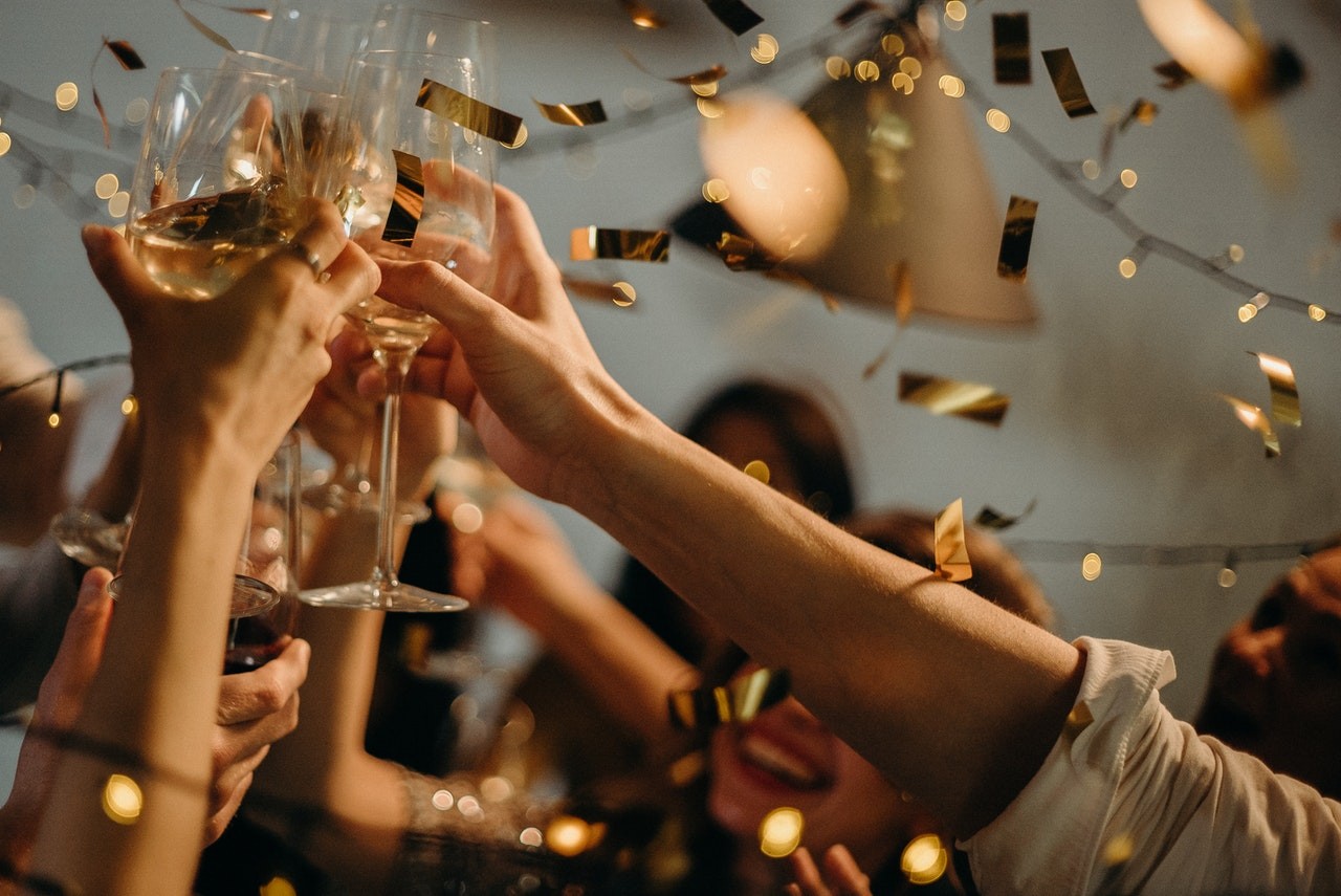People toasting with wine glasses - throw a housewarming party to reward friends for helping you move