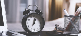 clock on a table signifying the time-frame of when you need to start preparing your office move