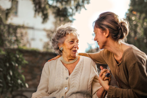 women helping elderly parent to move and talking