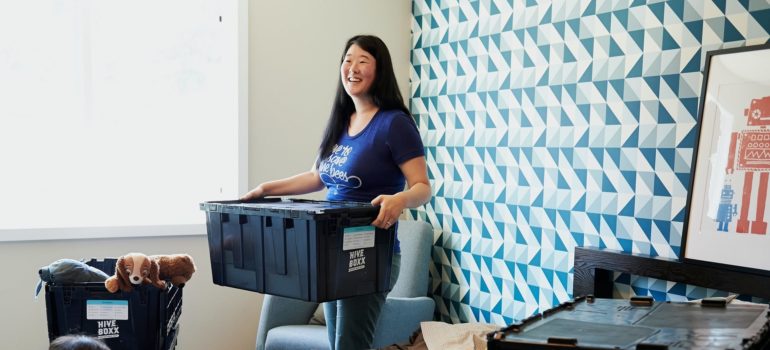 a woman holding a plastic container in the bedroom