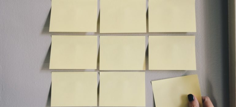 a woman placing sticky notes on the wall as a way of planning that can help to maximize space in a portable storage