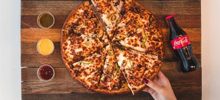a person taking a piece of pizza