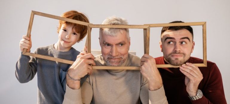 Grandfather, father and a son holding frames and posing for a picture.
