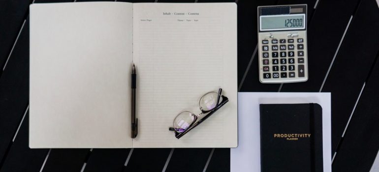 a notebook with glasses and a calculator near it