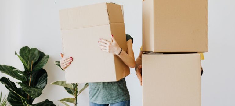 two people carrying moving boxes
