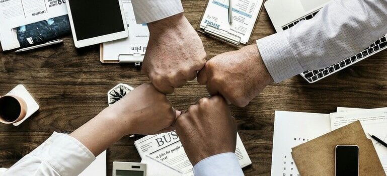 people doing a fist bump says that good coworkers are one of the reasons to start a business in Manhattan