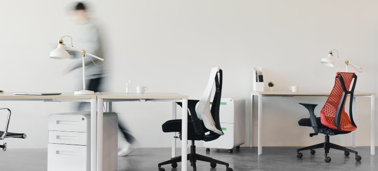 a silhouette of a man walking though an office while decluttering to represent how to safely relocate all your office items to Queens
