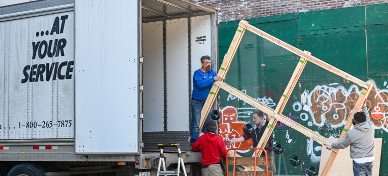 a moving crew handling a larger wooden frame into the moving truck