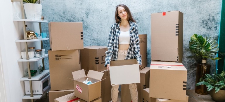 a woman holding a box and thinking how to organize a flawless move to Queens on short notice