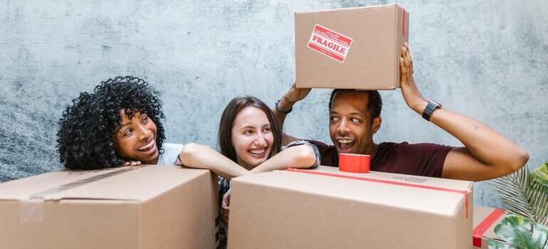 two women and one man holding boxes